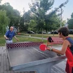 Couple playing on concrete ping pong table in the park.