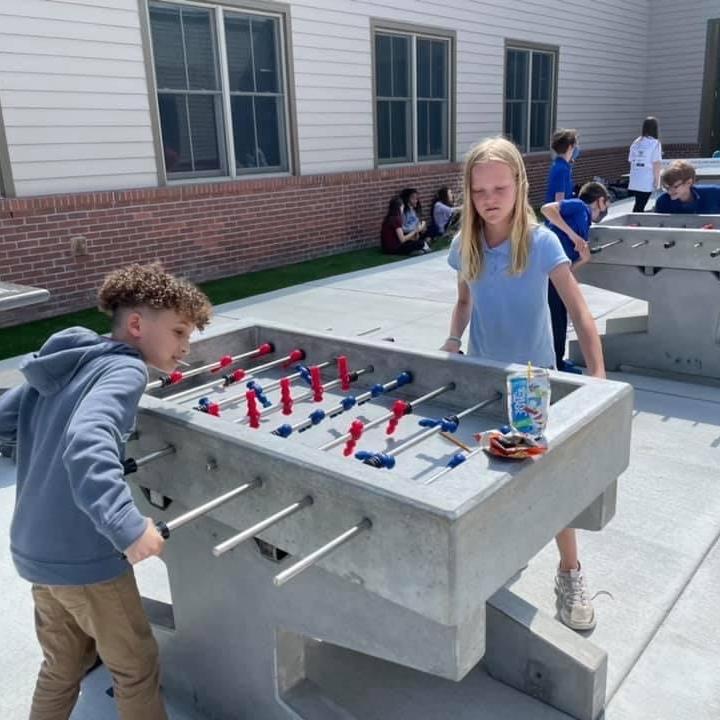 Kids playing in schoolyard concrete foosball table